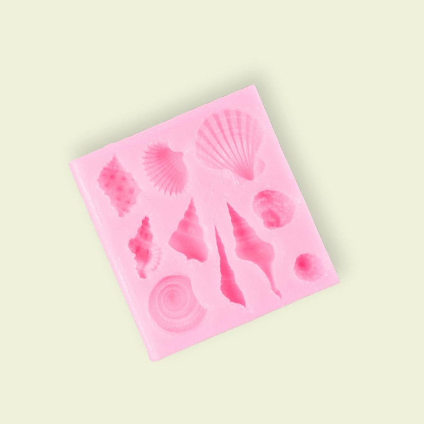 A pink silicone mold with various seashell shapes for food decoration.